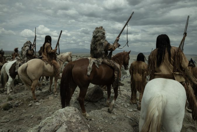 AMERICAN PRIMEVAL. (L to R) Tokala Black Elk as Buffalo Run, Derek Hinkey as Red Feather, Jeremy Gauna  as Tall Shadow, and Casey Bird, Hazen Herrera, Clarence Gilham, Tyler Still Smoking, Laramie Gadley, Jessi Edward, and Jayce Carlson as Wolf Clan Warriors in Episode 104 of American Primeval. Cr. Matt Kennedy, SMPSP/NETFLIX © 2023